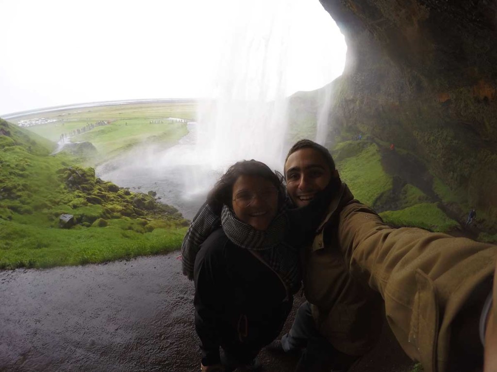 cachoeira de Seljalandsfoss, na Islândia. Em primeiro plano aparecem duas pessoas, com a cachoeira ao fundo 