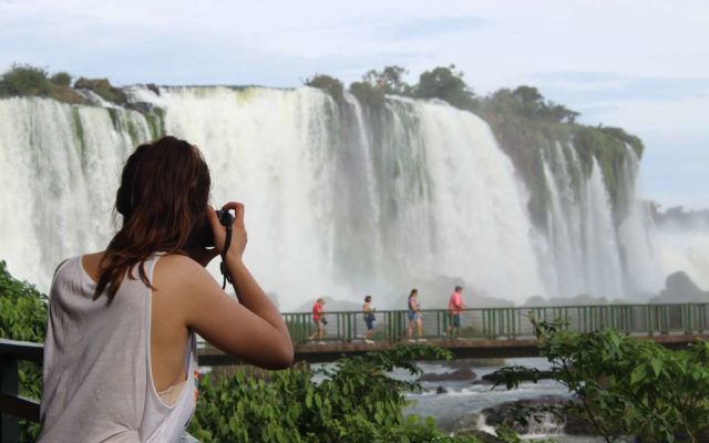 foto mostra turista tirando fotos de frente para as cataratas do iguacu em foz do iguacu no parana