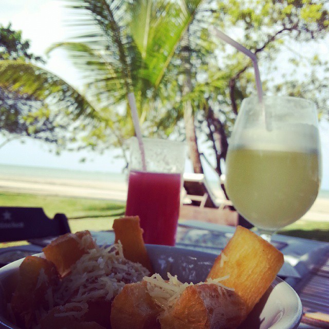 mandioca frita e suco de limao com coqueiros e praia ao fundo