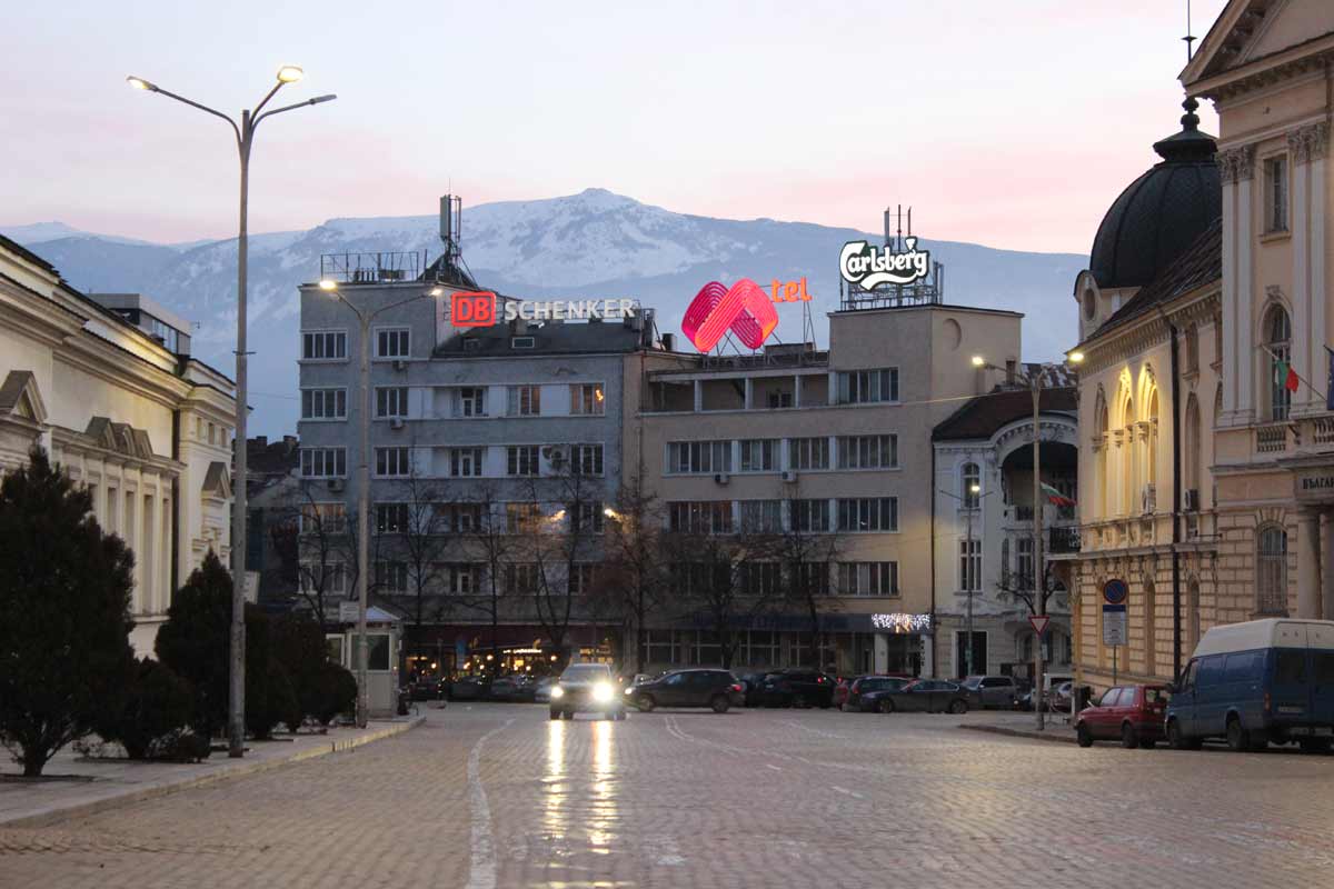 montanha vitosha ao fundo da foto. À frente, rua ladrilhada de Sófia, a capital da Bulgária