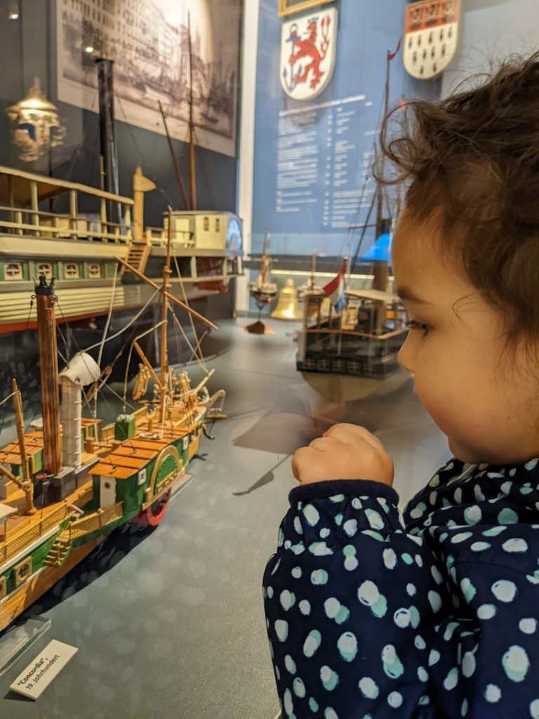 crianca observa navio de brinquedo atentamente