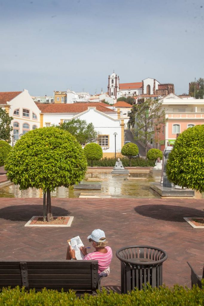 turista lê jornal no centro de silves. Vista para a catedral ao fundo